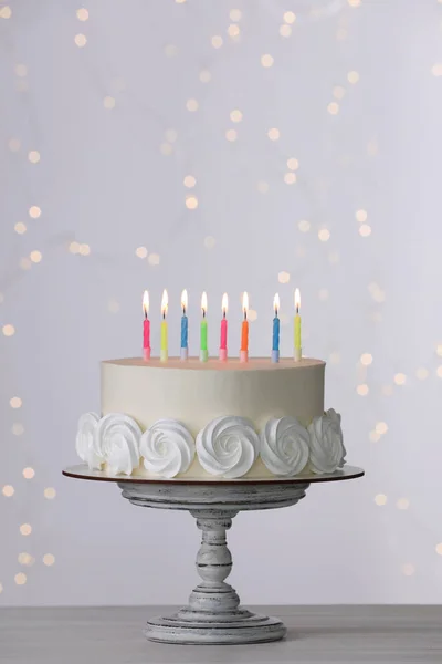Bolo Aniversário Com Velas Acesas Mesa Branca Contra Luzes Festivas — Fotografia de Stock