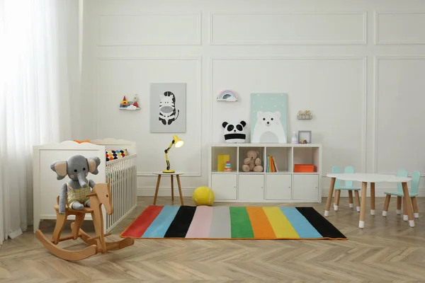 Cute baby room interior with stylish furniture and toys