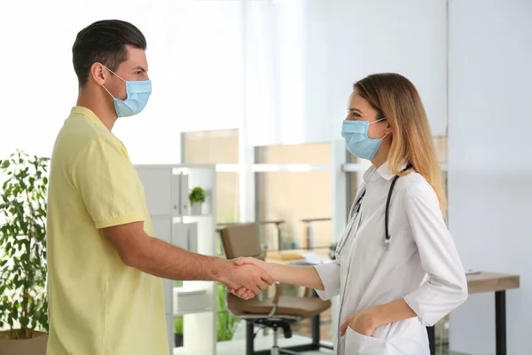 Médico Paciente Con Máscaras Protectoras Estrechando Las Manos Interiores — Foto de Stock