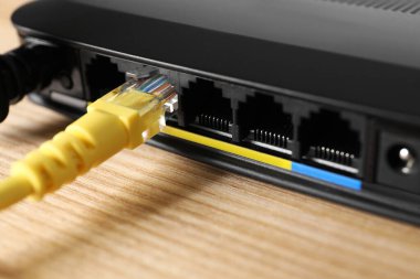 Tahta masadaki yönlendiriciye bağlı kablo, yakın plan. Kablosuz internet iletişimi