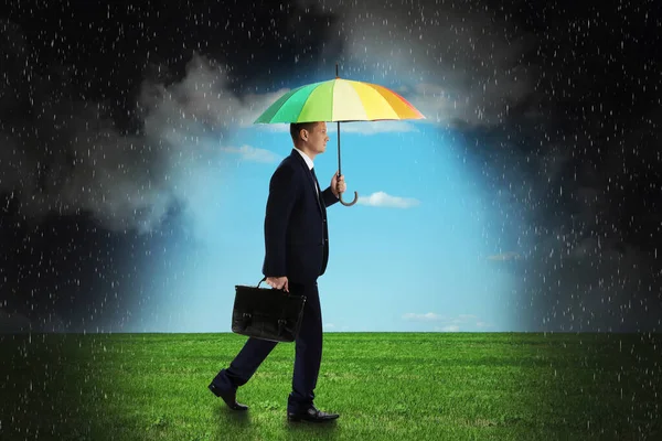 Businessman with umbrella under heavy rain. Insurance concept