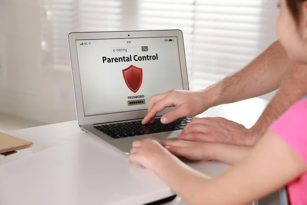 Father installing parental control app on laptop to ensure his child\'s safety at home, closeup