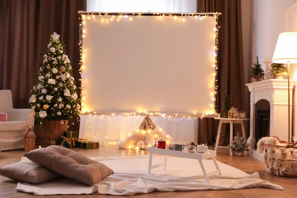 Blank video projector screen in room decorated for Christmas. Cozy atmosphere