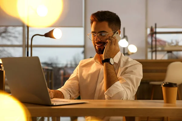 Ofiste Dizüstü Bilgisayarla Çalışan Bir Adam Akıllı Telefondan Konuşuyor — Stok fotoğraf