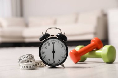 Alarm saati, mezura ve ahşap zemindeki dambıllar. Sabah egzersizi