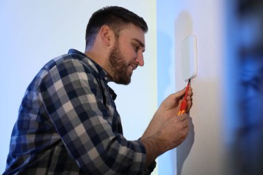 Adam evdeki ışık duvarına güvenlik alarmı kuruyor