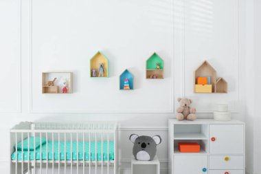 Bebek odasında renkli rafları olan duvarın yanında rahat bir beşik. İç tasarım