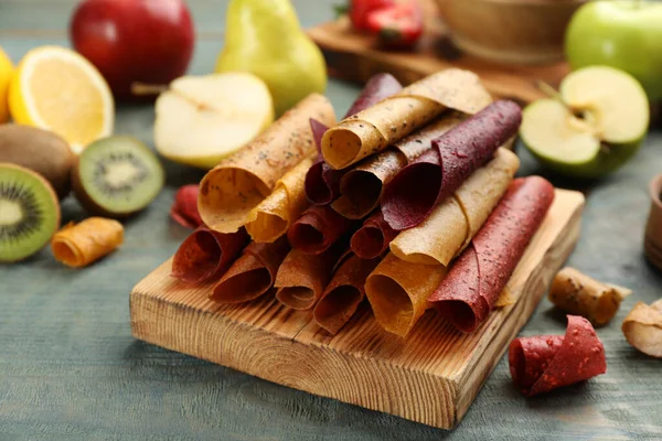 Composition with delicious fruit leather rolls on blue wooden table