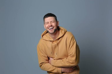 Gri arka planda gülen yakışıklı bir adam. Komik şaka.