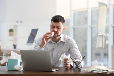Ofisteki masada burun spreyi kullanan hasta adam.