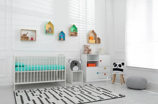 舒适的婴儿床靠近墙壁 婴儿房间里有彩色架子 室内设计 — 图库照片