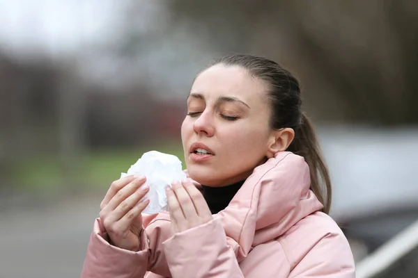 紙組織を持つ病気の女性は屋外でくしゃみ — ストック写真