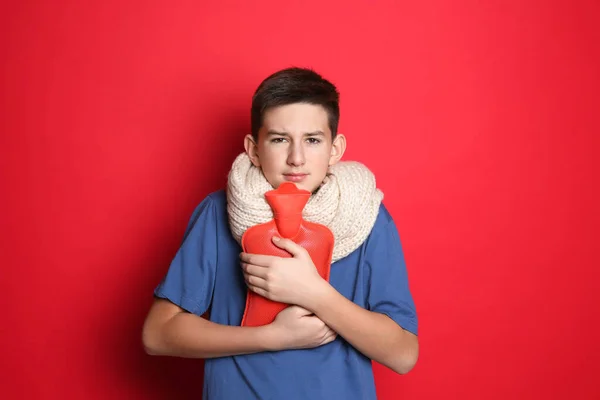 Ziek Tiener Jongen Met Warm Water Fles Rode Achtergrond — Stockfoto