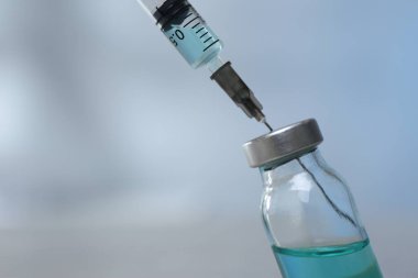 Şırıngayı bulanık arka plandaki ilaç şişesiyle dolduruyorum. Yakın plan. Metin için boşluk