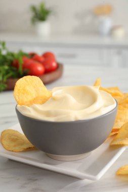 Beyaz mermer masada patates cipsi ve mayonez, metin için yer var.