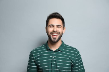 Genç adam açık gri arka planda gülüyor. Komik şaka.