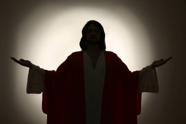 İsa 'nın silueti. Renkli arka planda kolları açık.