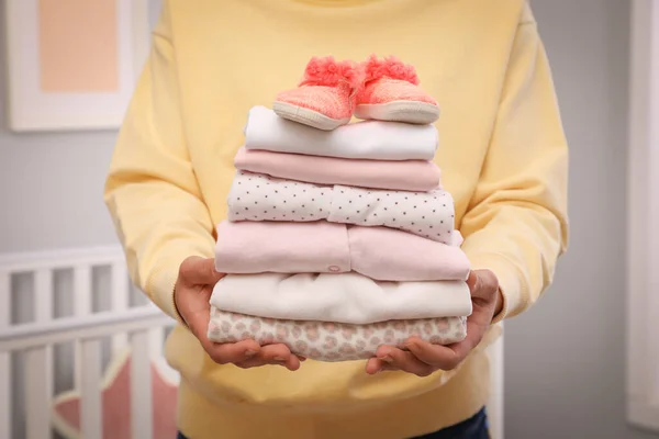 Frau Hält Stapel Von Mädchenkleidung Und Booties Drinnen Nahaufnahme — Stockfoto