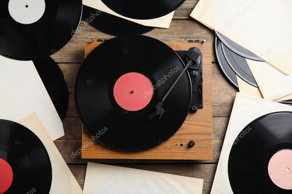 Modern player and vinyl records on wooden background, flat lay