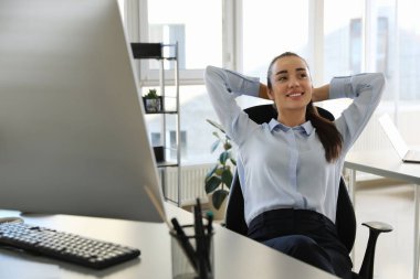 İş yerindeki ofis sandalyesinde dinlenen genç iş kadını