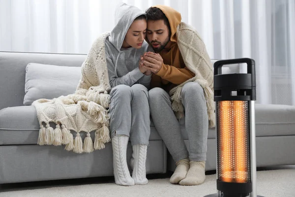 一对年轻夫妇在家里靠近电热器取暖 — 图库照片