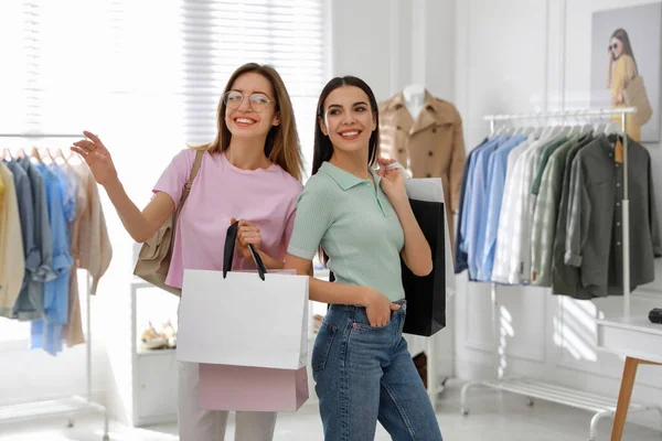 現代のブティックで服を選ぶショッピングバッグを持つ若い女性 — ストック写真