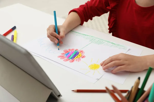 Little girl drawing on paper with pencil at online lesson indoors, closeup. Distance learning