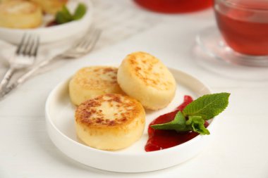 Lezzetli süzme peynirli krep, beyaz masada reçel ve nane.