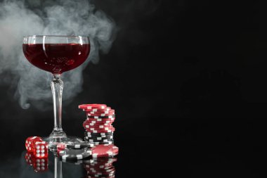 Kumarhane fişleri, zarlar ve bir bardak şarap dumanlı arka planda. Metin için boşluk
