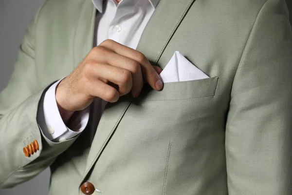 男人在他西服的胸袋里缝制手帕 灰色背景 — 图库照片