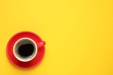 Sarı arka planda kırmızı bardakta, koyu kahve, üst manzara. Metin için boşluk