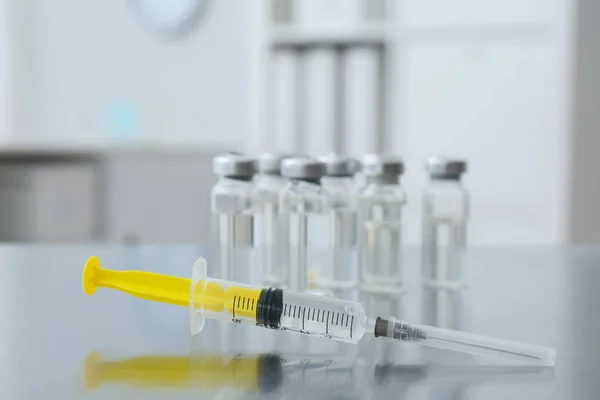 Syringe and vials with medicine on table indoors