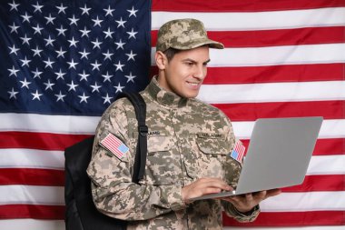 Amerikan bayrağına karşı sırt çantalı ve dizüstü bilgisayarlı öğrenci. Askeri eğitim