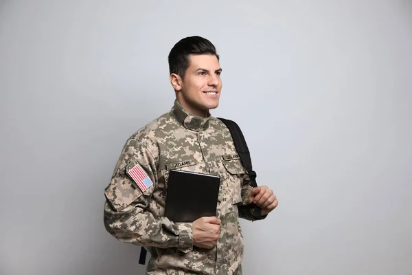 ライトグレーの背景にバックパックとタブレットでキャデット 軍事教育 — ストック写真