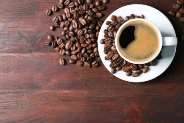 Bir fincan sıcak aromatik kahve ve ahşap masada kavrulmuş fasulye. Metin için boşluk