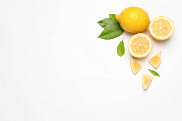 Flat lay composition with fresh juicy lemons and green leaves on white background. Space for text