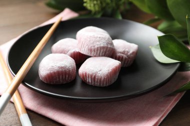 Lezzetli mochi ile siyah tabak ve ahşap masa üzerinde çubuklar. Geleneksel Japon tatlısı