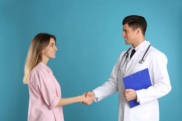 医者と患者の握手上のライトブルーの背景 — ストック写真