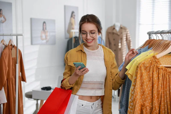 Mujer Joven Con Teléfono Elegir Ropa Cerca Rack Boutique Moderna — Foto de Stock