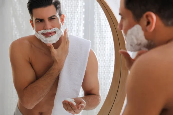 Bonito Homem Aplicando Espuma Barbear Perto Espelho Banheiro — Fotografia de Stock