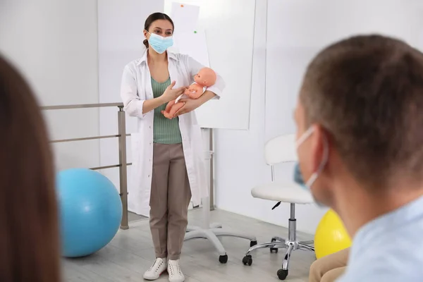 Lékař Ochranné Masce Učí Těhotnou Ženu Jejího Manžela Starat Dítě — Stock fotografie