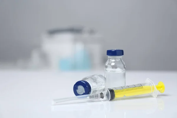 Syringe and vials on white table. Space for text