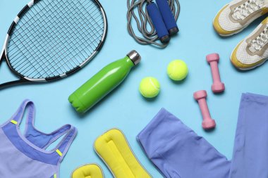 Açık mavi arka planda spor ekipmanları ile düz konum