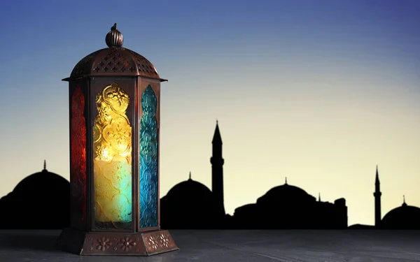 Decorative Arabic lantern on stone surface and silhouette of mosque at sunset on background, space for text