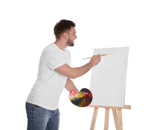 男は白を背景にイーゼルで筆で絵を描く 若手作家 — ストック写真