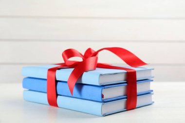 Beyaz masada kırmızı kurdeleyle bağlanmış farklı kitaplar.