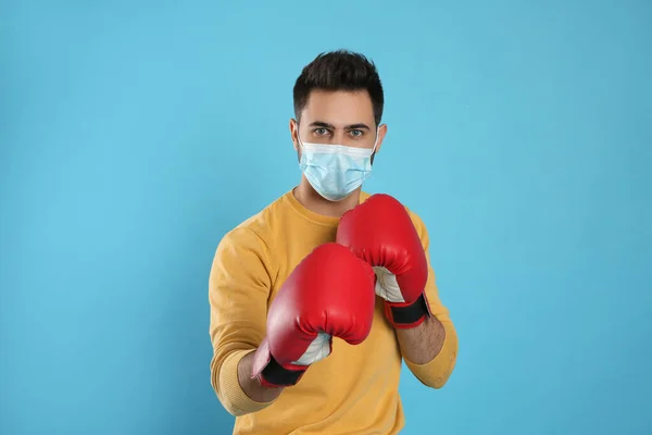 Man Med Skyddsmask Och Boxningshandskar Ljusblå Bakgrund Starkt Immunitetsbegrepp — Stockfoto