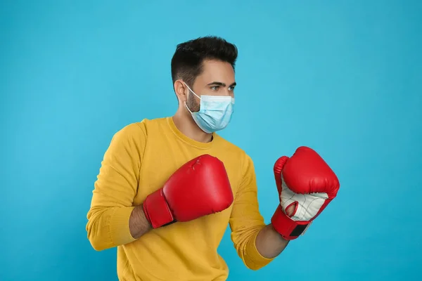 Man Med Skyddsmask Och Boxningshandskar Ljusblå Bakgrund Starkt Immunitetsbegrepp — Stockfoto