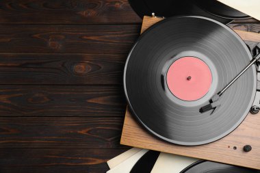 Ahşap arka planda modern oyuncu ve vinil plaklar, düz yatış. Metin için boşluk