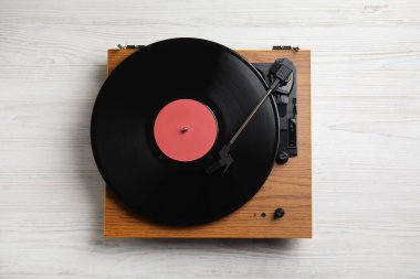 Beyaz ahşap arka planda diski olan modern vinil plak çalar, üst görünüm